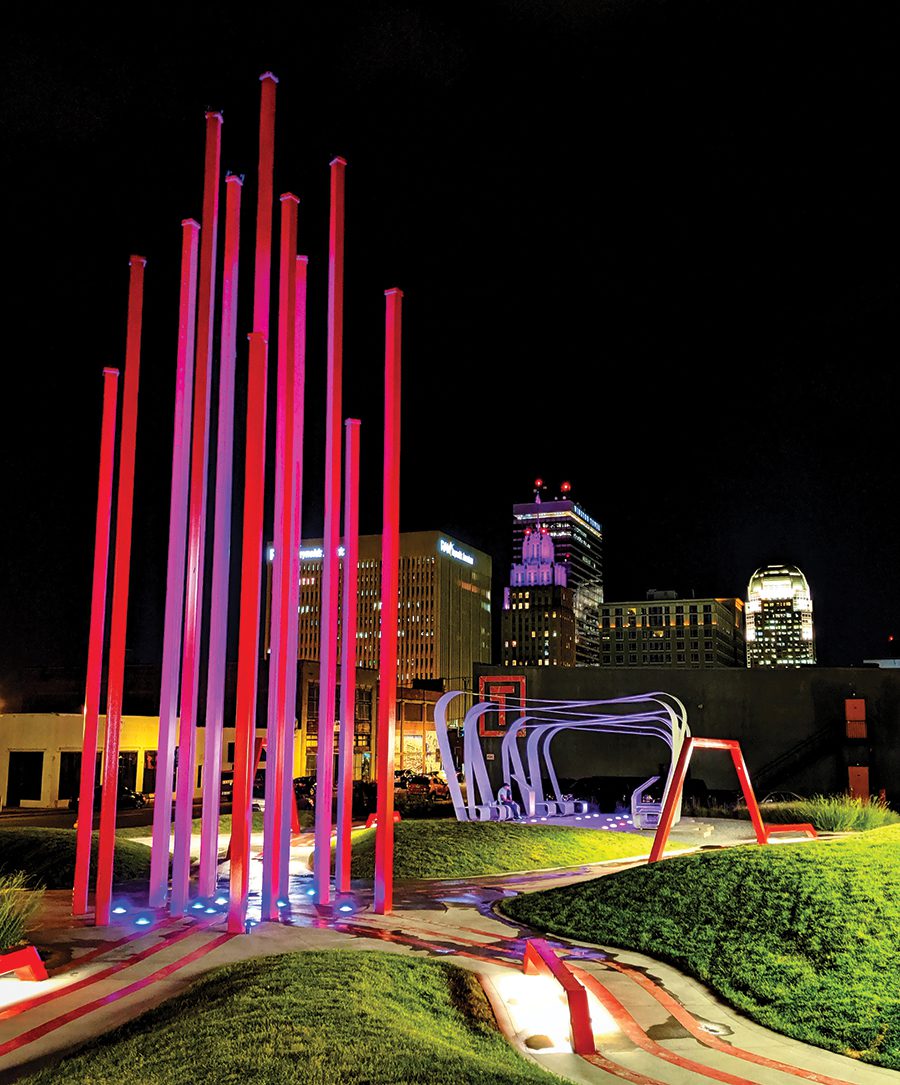 A pink, red, and purple art installation facing the cityscape in Winston-Salem, NC. 