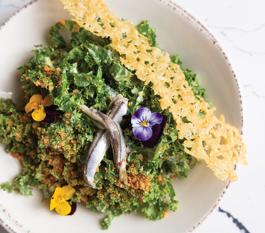 A kale salad with assorted flowers and parmesean crisp garnishes