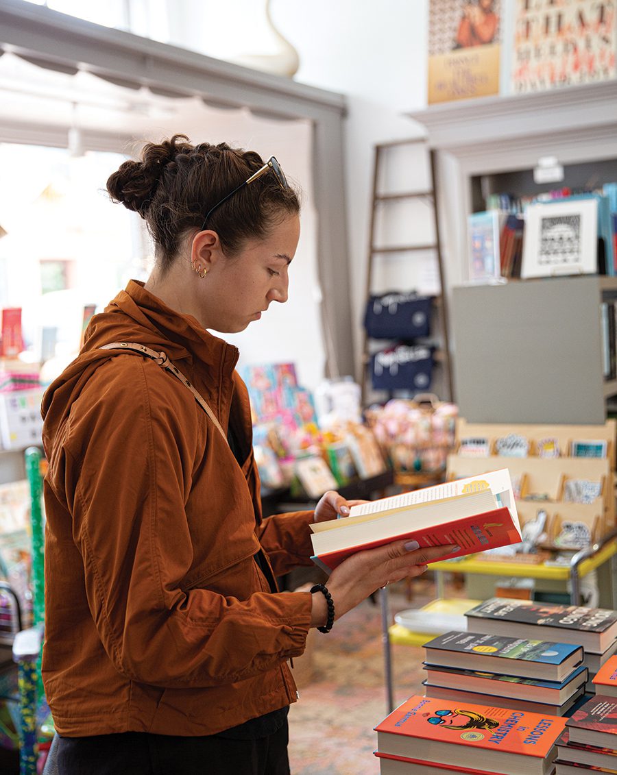A woman stands in a bookstore checking out a new book
