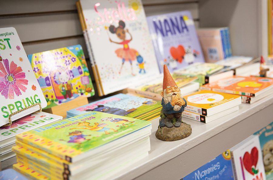 A group of books is displayed with a miniature gnome figure in front of it at Main Street Books in Davidson, NC. 