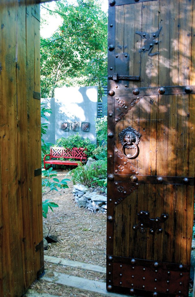 Antique Chinese doors open into the path of a south Charlotte shade garden. 