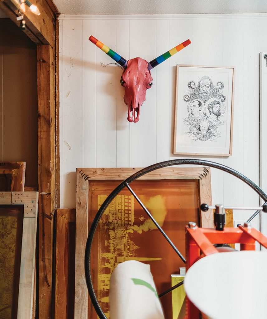 Grammy award winning musician, Scott Avett's studio with screen print frame, print press, with a print etching framed on the wall next to a pink and rainbow animal skull. 