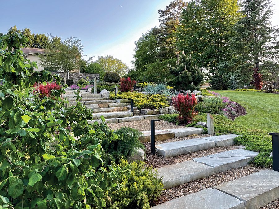 A front lawn landscaped wtih staggered stone steps and flower beds on either side.
