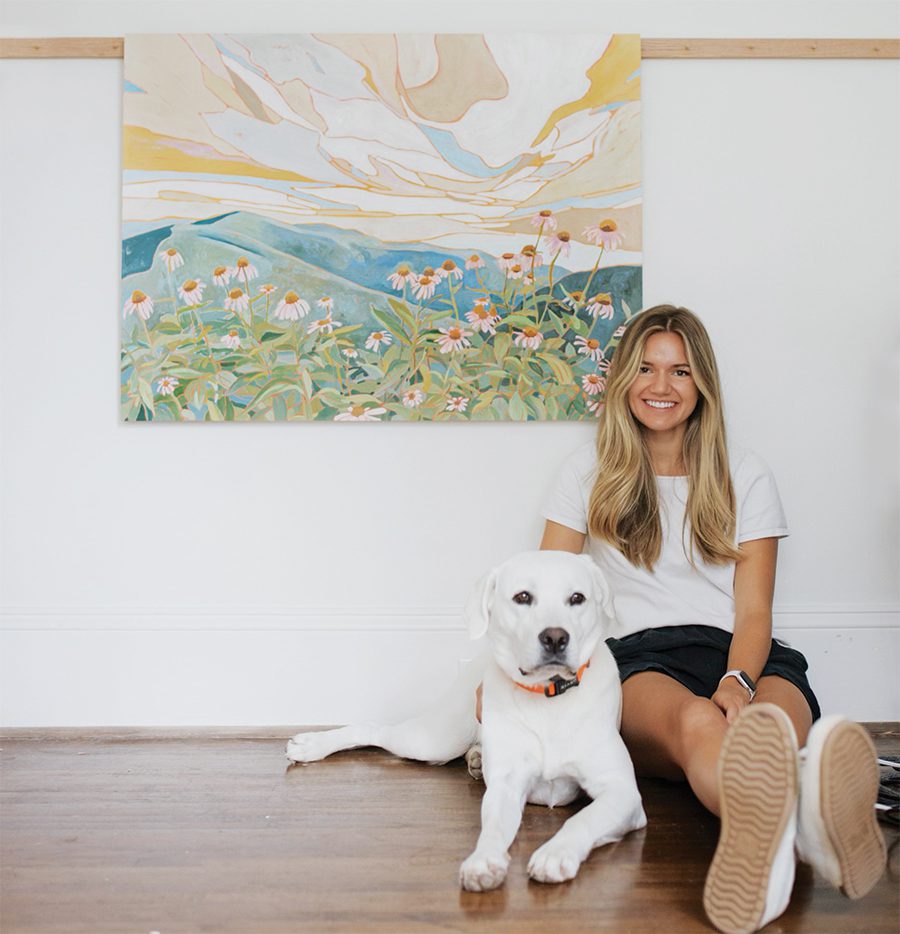 Mary Benson poses with her dog with one of her large works of art in the background.