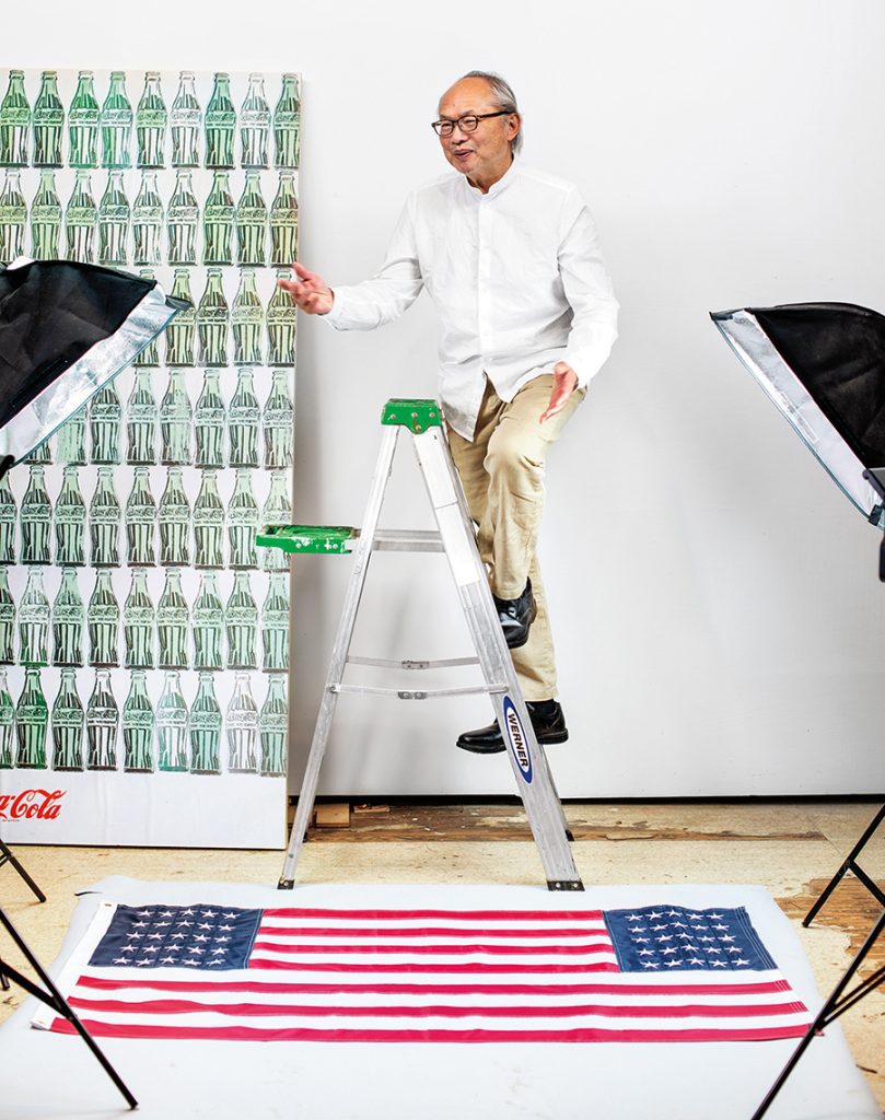 Artist Mel Chin stands on ladder surrounded by his artwork.