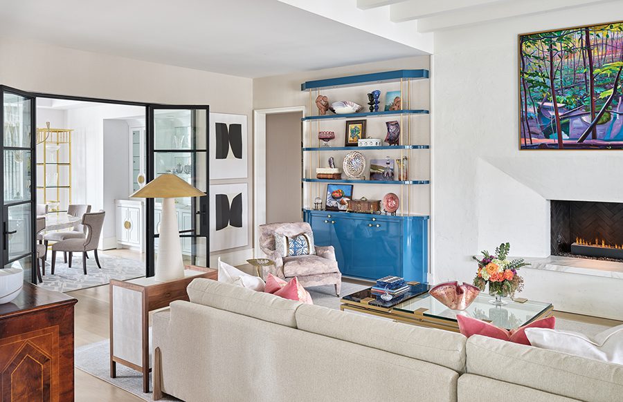 Custom shelves and a vibrant painting by Ohio artist Charles Basham, sourced from Jerald Melberg Gallery, brighten the neutral-toned family room.