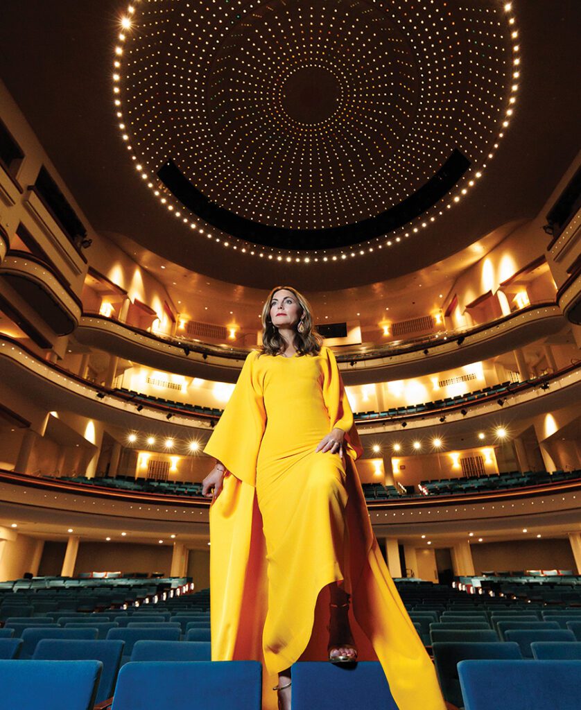 Sabina Schlumberger stands in a yellow dress in Belk Theatre in uptown Charlotte.