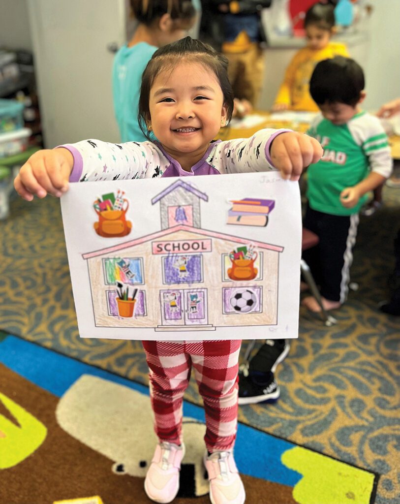A child holds a picture she colored at Refugee Support Services in Charlotte.
