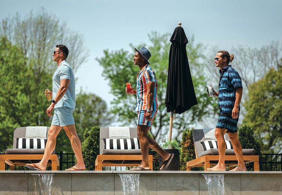 Three men walk by the pool in south Charlotte during a style shoot for SouthPark Magazine.