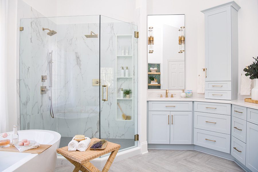A freestanding tub next to a shower with marble tile. Pale blue cabinets anchor the wall space.