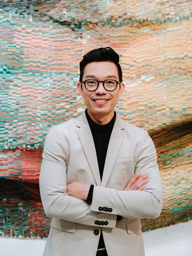 Artist Kenny Nguyen stands in front of one his painted silk sculptural pieces of art. 