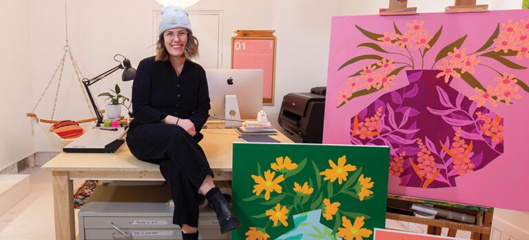 Artist Bailey Schmidt sits in her studio surrounded by her artwork