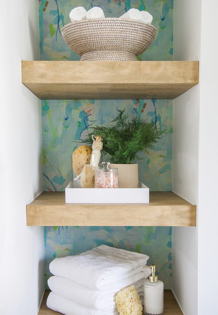 A storage nook with modern wood shelves in a bathroom designed by Dipped Interiors. 