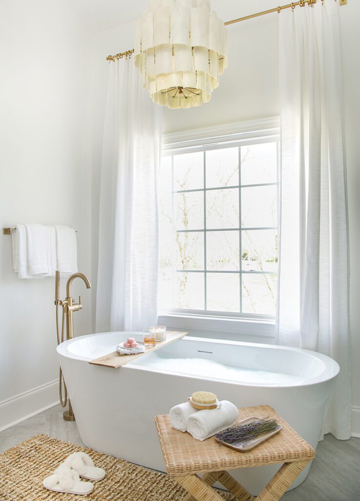 A freestanding tub by a window in a bathroom redesigned by Dipped Interiors.