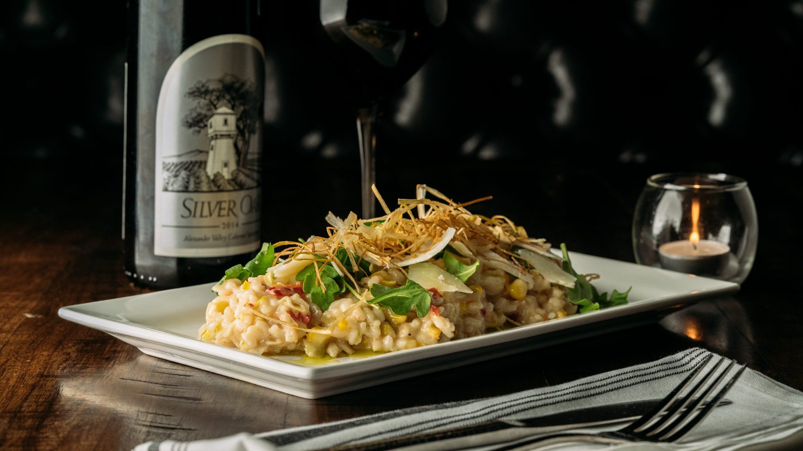 A plate of charred corn risotto with a glass of wine from The Cellar at Duckworth's in uptown Charlotte.