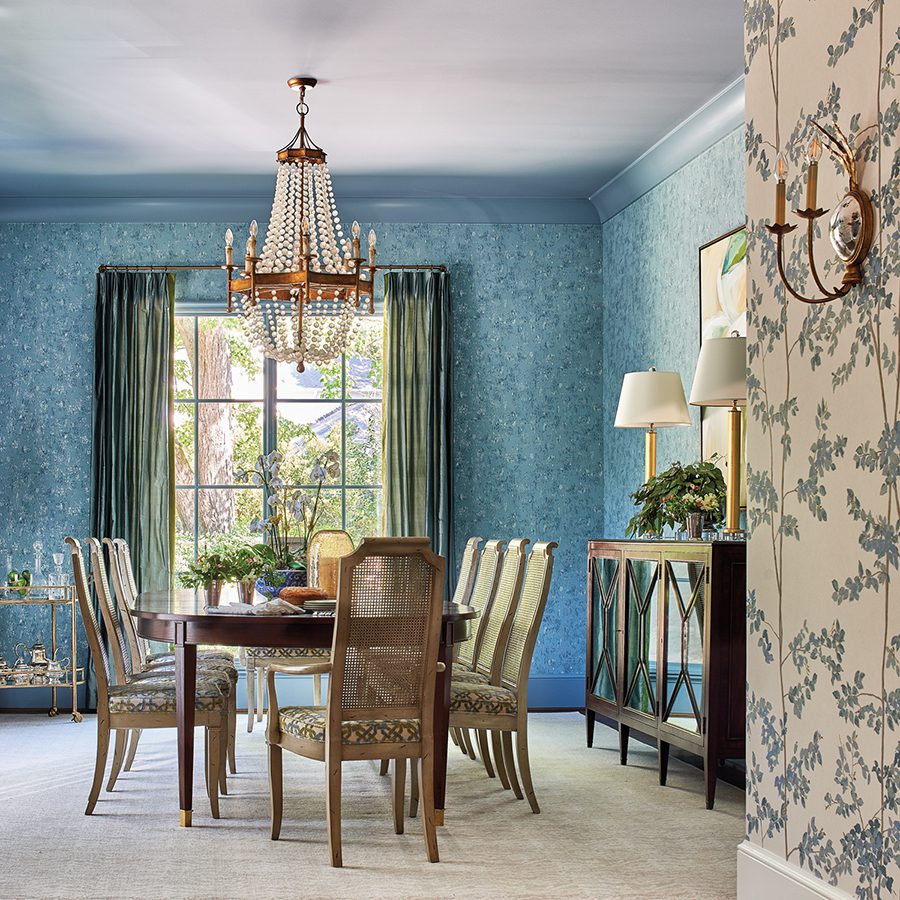 This dining room with blue wallpaper designed by Casey Maslanka has updated chairs that belonged to the homeowner's grandmother.