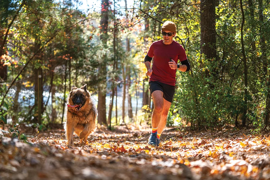 Man running with dog at Whitewater Center's Off Leash a 70-acre dog park