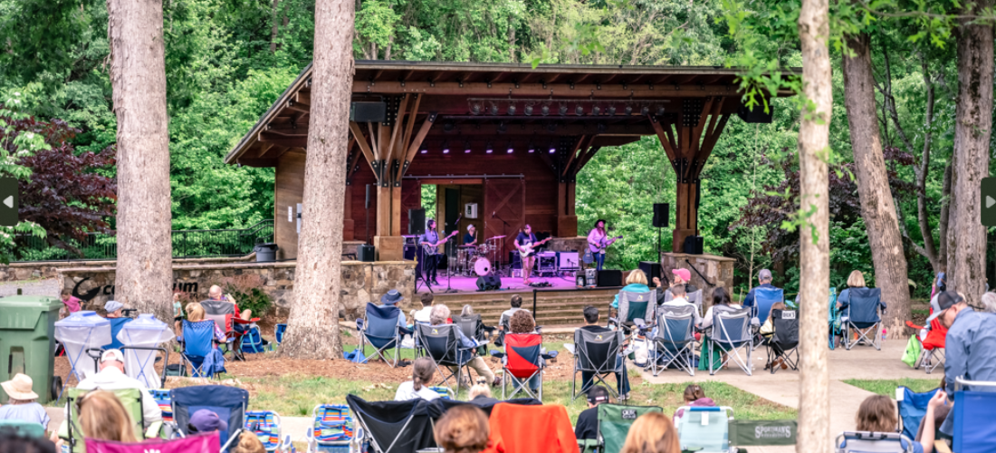 People sitting outside listening to music during the Anne Springs Close Greenway Summer Concert Series near Fort Mill, S.C.