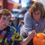 Volunteer Linda Riedel assists Ben, the author’s son, at a group outing at Bowlero in Matthews