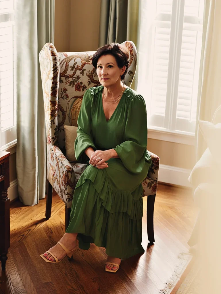 Author Valerie Bauerlein sitting in a chair in front of two windows