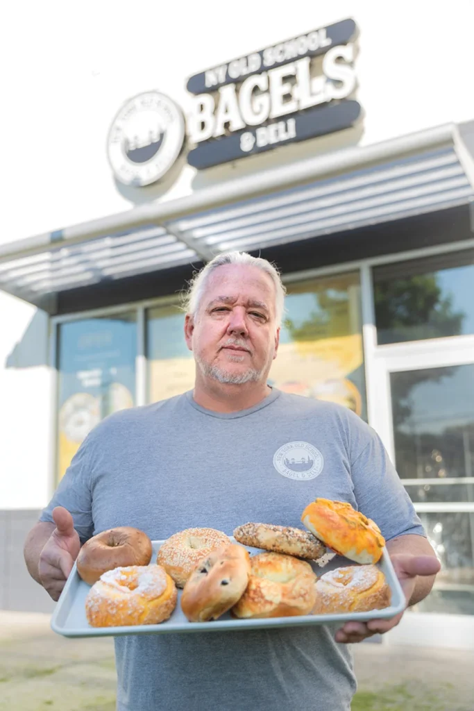 Owner Mark Stordeur holding tray of bagels in front of New York Old School Bagel & Deli