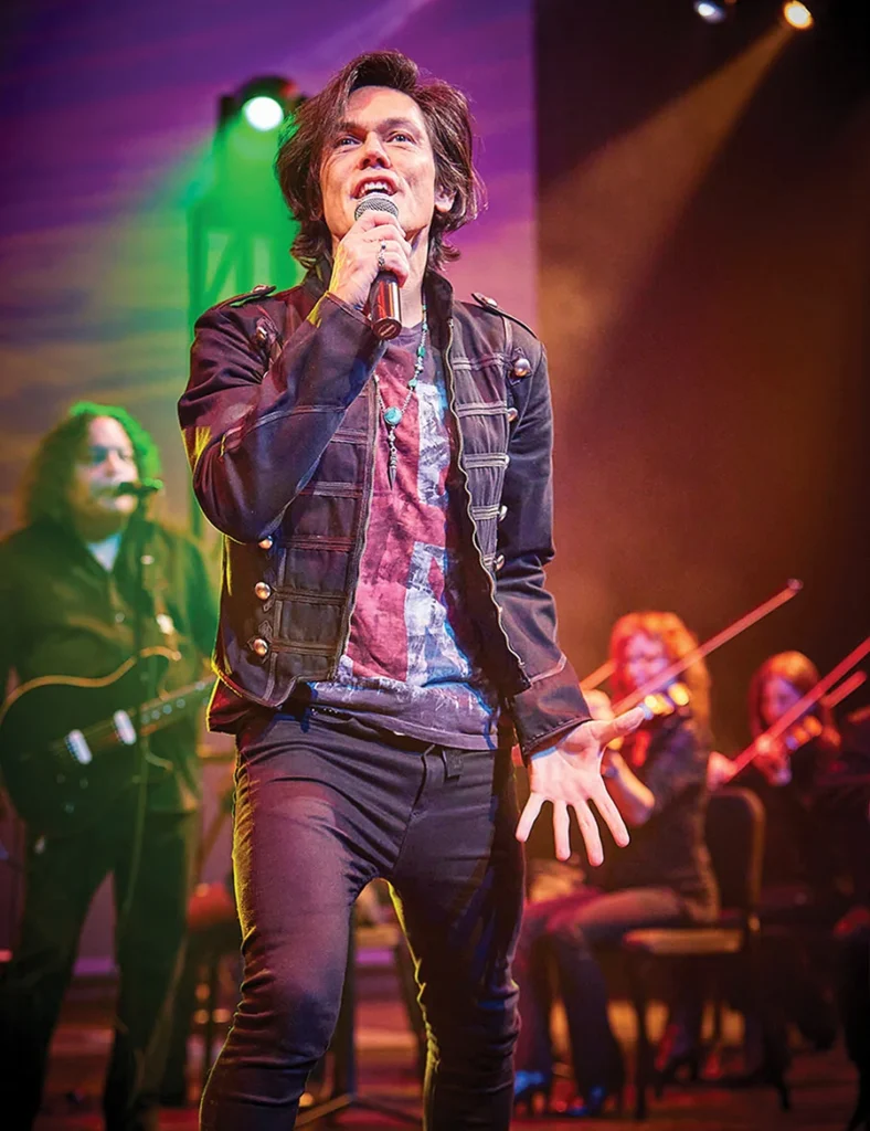 A man on stage singing The Music of Queen