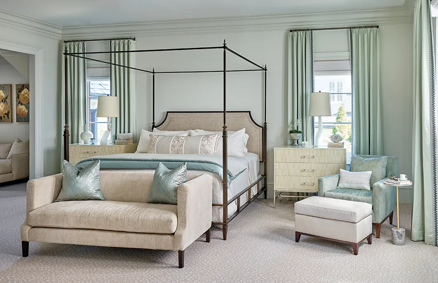In the primary bedroom, a variety of textures adds interest to the soft color palette. A four-poster bed by Modern History is layered with velvet, silk and cotton bedding. Theodore Alexander faux-bone chests of drawers flank the bed.