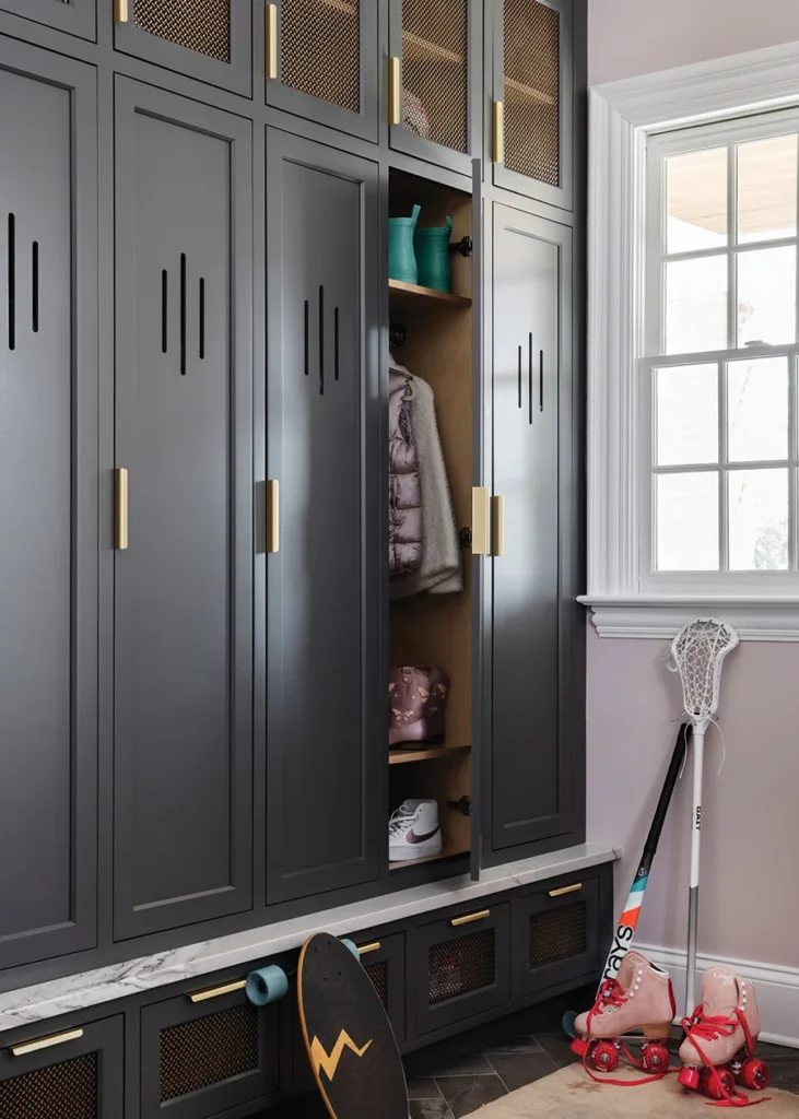 In the mudroom, custom lockers are painted a dark gray, Iron Mountain by Benjamin Moore. Each locker offers hooks, shelves and USB chargers to help keep the children organized.