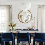 A Soho Home chandelier illuminates the dining room, where blue velvet CB2 chairs surround the table.