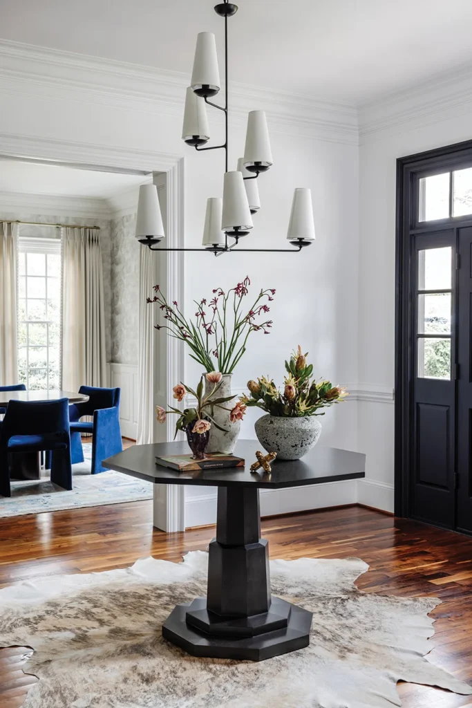 A black octagonal table by Noir greets guests in the entry hall. Visual Comfort’s Fontaine chandelier adds a minimalist, modern aesthetic to the space.