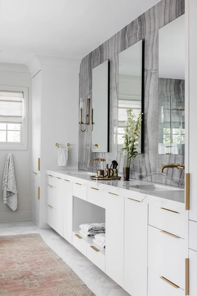 A porcelain slab from Walker Zanger accents the wall in the primary bathroom. Brass cabinet hardware is from Bird Hardware.