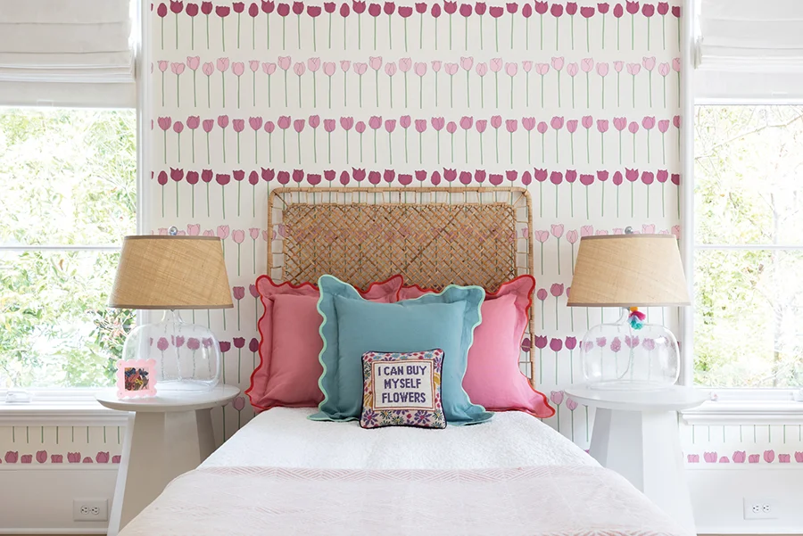 The designers used wallpaper throughout the girls’ rooms. “It is such an easy way to add color, youthfulness and a sense of play to an area,” Peyton says. The tulip wallpaper is by Schumacher. The rattan headboard from IKEA adds texture. Pillows are by Furbish Studio, and the lamps are Regina Andrew.