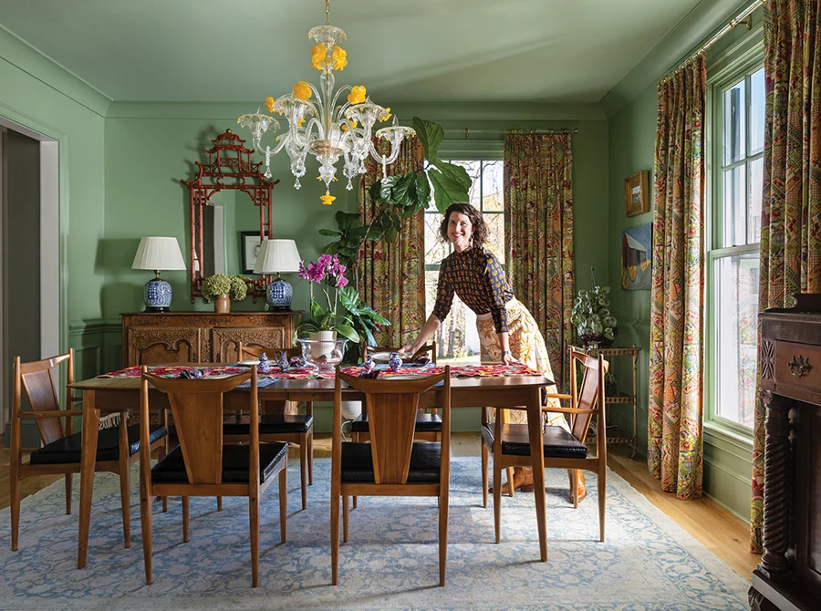 The midcentury-modern dining room table and chairs were purchased at an estate sale. The Murano chandelier was a special custom purchase from Italy. The wall color is Farrow & Ball Breakfast Room Green.