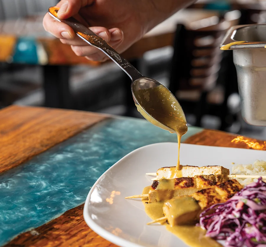 Drizzling peanut butter dipping sauce on tofu