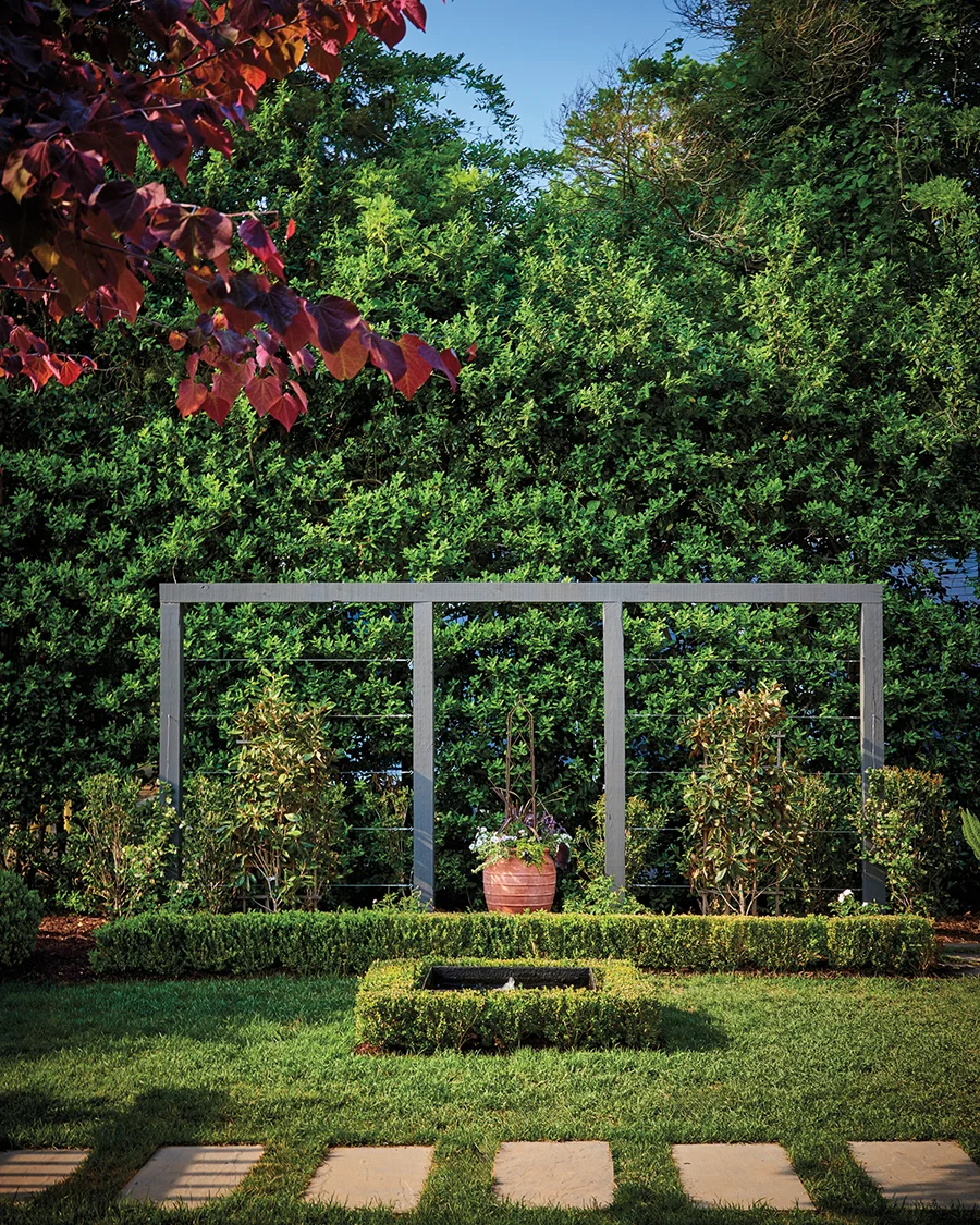 Ligon designed the lateral structure in the front yard, where he espaliered two Little Gem magnolia trees on either side of a large terracotta urn.