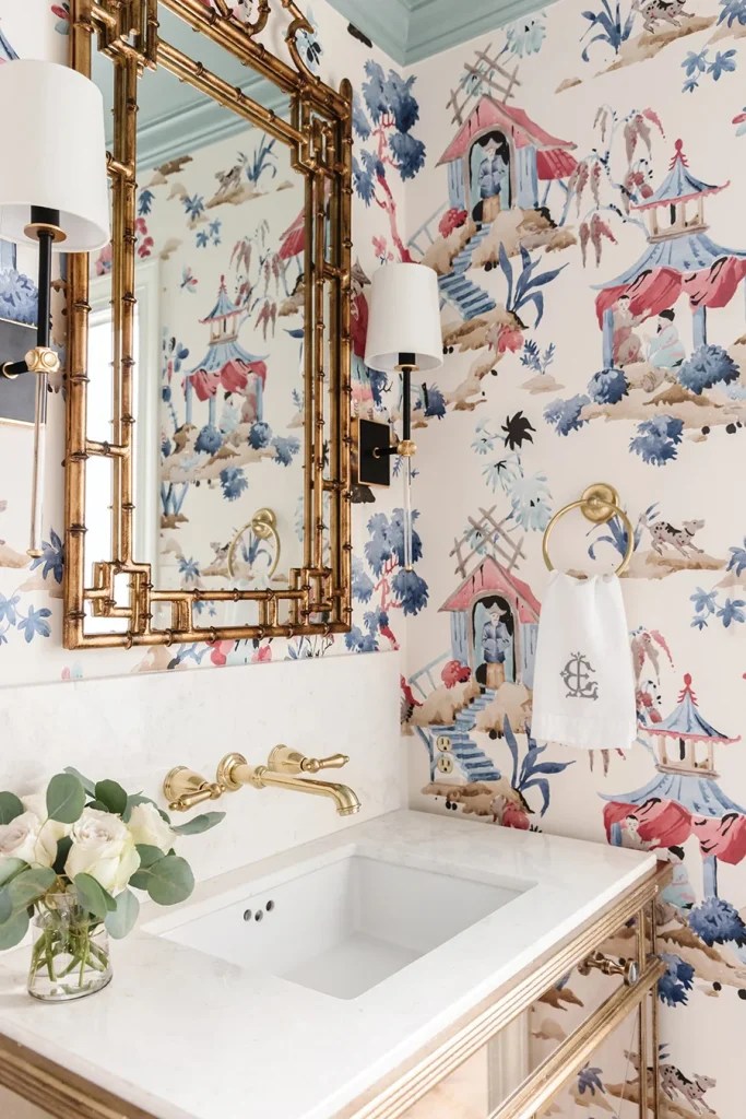 Chinoiserie-inspired wallpaper, black sconces and a painted ceiling make a bold statement in the powder room.