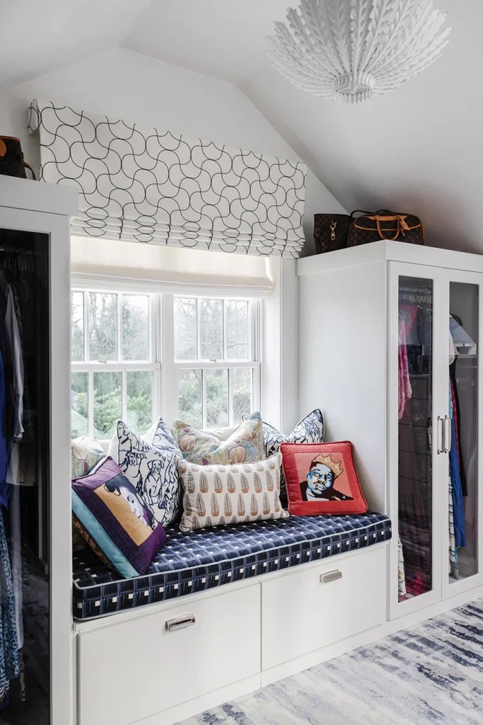 In the closet of the primary suite, playful needlepoint pillows — made by the homeowner — add a pop of color and whimsy.