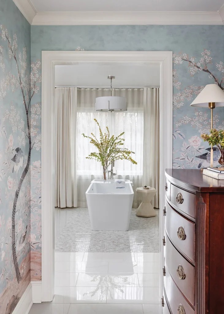 A pass-through space between the primary bedroom and bathroom is adorned with House of Harris “Fauna” wallpaper panels.