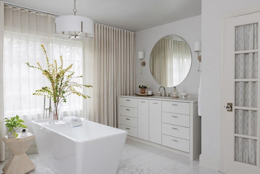 In the spa-like primary bath, sheer panels behind linen draperies ensure privacy year-round.